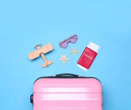 Pink suitcase and beach objects on blue background, flat lay Fotos de archivo