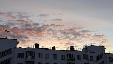 Pink sunset clouds spreading over modern apartment building complex with roof Stock Photos