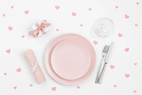 Pink table setting with confetti hearts, gift, napkin on a white background.  Stock Photos
