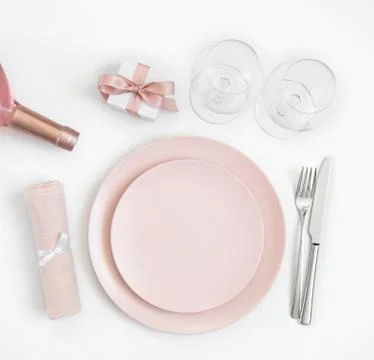 Pink table setting with wine, gift, napkin on a white background.  Stock Photos