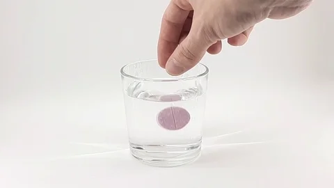 Pink tablet dissolves in a glass of water Stock Footage 124830767