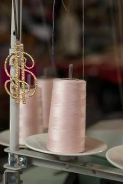 Pink Thread in a Machine Spool Beside Dollar Sign Pendant Stock Photos