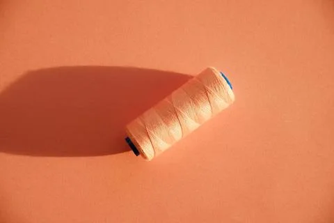 Pink thread spool on a pink background in direct sunlight, sewing concept Stock Photos
