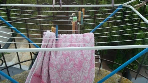A pink towel hanging on a folding drying rack on the balcony flutters in th.. Stock Footage 331255108