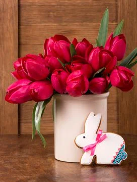 Pink tulips and easter bunny cookie on wooden background. Stock Photos