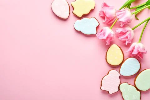 Pink tulips with easter gingerbread eggs located in a row on pink background. Stock Photos