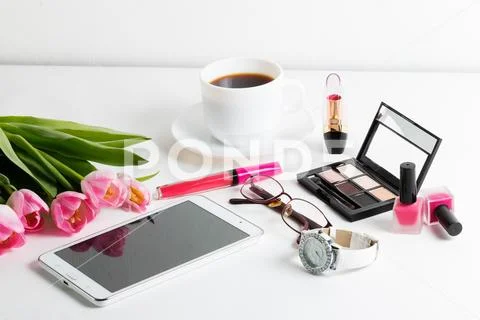 Pink tulips, white tablet, cosmetics, wristwatch, notepad, cup of coffee, gla Stock Photos