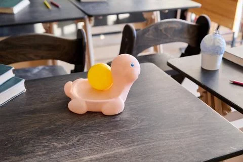 Pink turtle toy with yellow shell sitting on dark wooden table in bright cl.. Stock Photos
