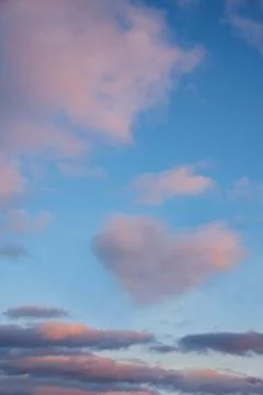 Pink vanilla clouds on a blue sunset sky Stock Photos