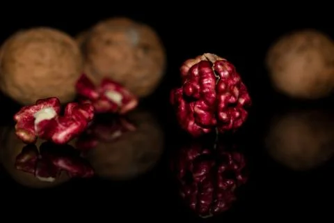 Pink walnut kernels on a dark reflective table. Black background Stock Photos