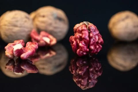 Pink walnut kernels on a dark reflective table. Black background Stock Photos