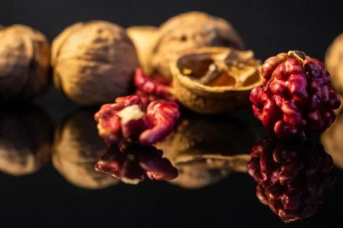 Pink walnut kernels on a dark reflective table. Black background Stock Photos