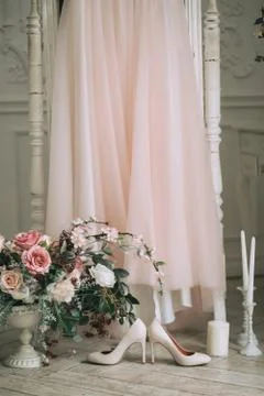 Pink wedding dress in the studio, besides beige shoes, a bouquet of roses and Stock Photos