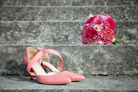 Pink wedding shoes and wedding bouquet on a concrete stairs Stock Photos