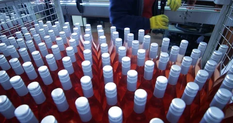 Pink wine bottles in packaging stage. Person grabbing glass bottles Stockbeeldmateriaal 95301294