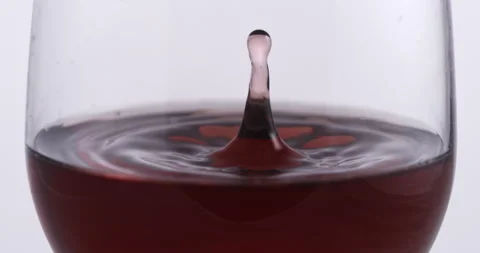 Pink wine drop is falling with splashes in transparent glass in wine cellar Stock Footage 268472059