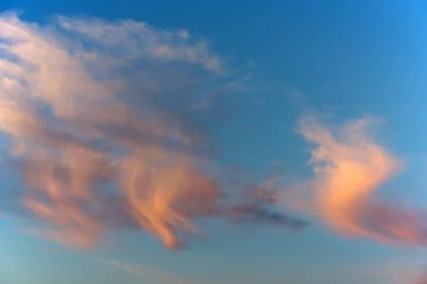 Pink wispy clouds catch the sun's light Stock Photos