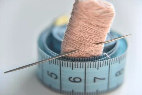 Pinkish beige threads with needle and measuring tape Stock Photos