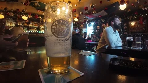 Pint of beer on table inside traditional pub Dublin Ireland festive interior Stock Footage 333841388