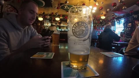 Pint of beer on table with person using smartphone in pub Dublin Ireland Stock Footage 333862493