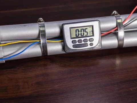 Pipe bomb with an clock timer to trigger detonation, on wooden table Foto stock