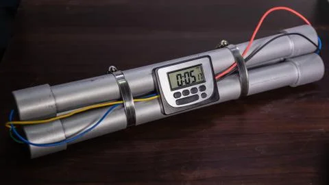 Pipe bomb with an clock timer to trigger detonation, on wooden table Stockfoto's
