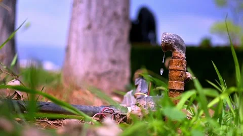 A pipe coming from the ground is leaking drops of water. Stock Footage 294017722
