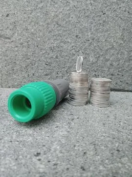 Pipe Connector Lying Beside Two Coin Stacks with One Upright Coin 스톡 사진