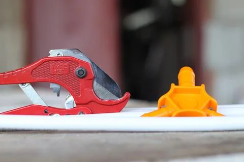Pipe cutters lie on a background of white plastic pipes. Tools Stock Photos