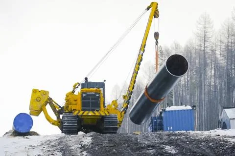 Pipe layer holds section of pipe on a crane for gas pipeline installation Stock Photos