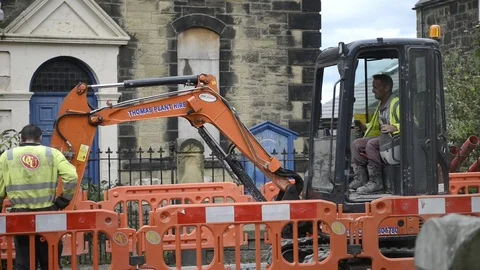 Pipe laying roadworks. Workmen and digger. Close up. Stock Footage 111593335