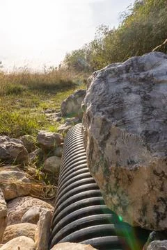 A pipe is next to a large rock Foto stock