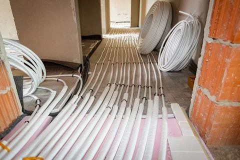 Pipe system of floor heating mounted in residential building under constructi Fotos de archivo