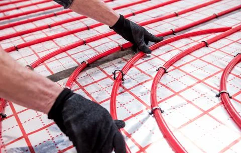 Pipefitter install system of underfloor heating system at home Stock Photos