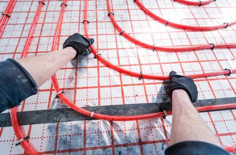 Pipefitter install system of underfloor heating system at home Stock Photos