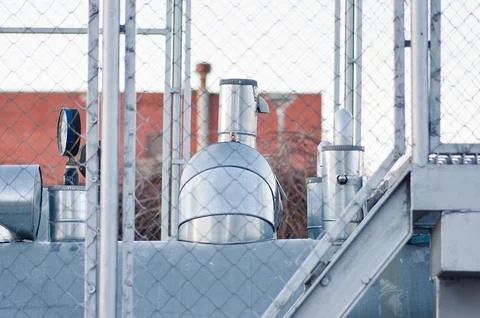 Pipeline and pipeline elements behind a mesh fence. Stock Photos