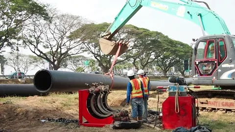 A pipeline construction team is moving a HDPE pipe using an excavator. Stock Footage 159230067