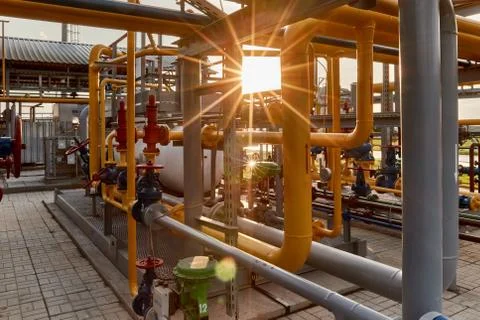 Pipeline system at gas processing plant lit by sunset sun Stock Photos