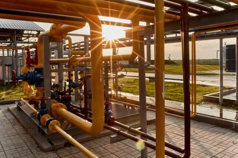 Pipeline system at gas processing plant lit by sunset sun Stock Photos