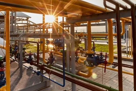 Pipeline system at gas processing plant lit by sunset sun Stock Photos