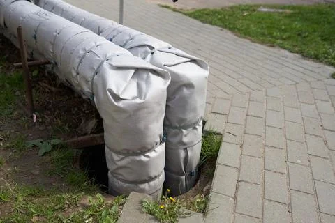 Pipes of the above-ground heating main with damaged insulation of the city Stock Photos