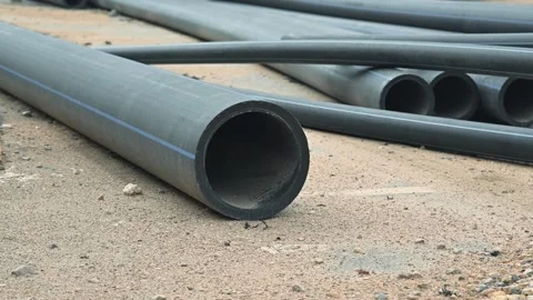 Pipes are laid out on a construction site, showing different lengths and Видео 344676004