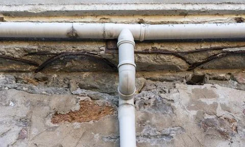 Pipes attached to an old stone wall in a building showing wear and tear wit.. Stock Photos
