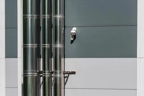 Pipes run vertically along a gray wall in an industrial area Фото