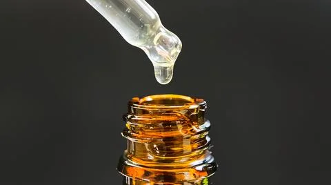 Pipette with a drop of face serum or oil for the face and hyaluronic acid on Stock Photos