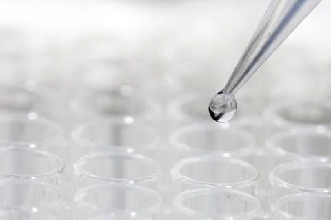 Pipette with drop of liquid over test tubes Stock Photos
