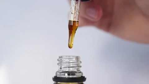 A pipette / dropper dispensing a drop of solution / medicine / oil Stock Footage 144893416