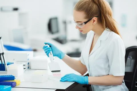 Pipette dropping a sample in a test tube. Laboratory assistant analyzing blood Foto stock
