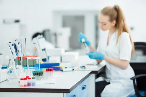 Pipette dropping a sample in a test tube. Laboratory assistant analyzing blood Stock Photos