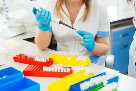 Pipette dropping a sample in a test tube. Laboratory assistant analyzing blood Stock Photos